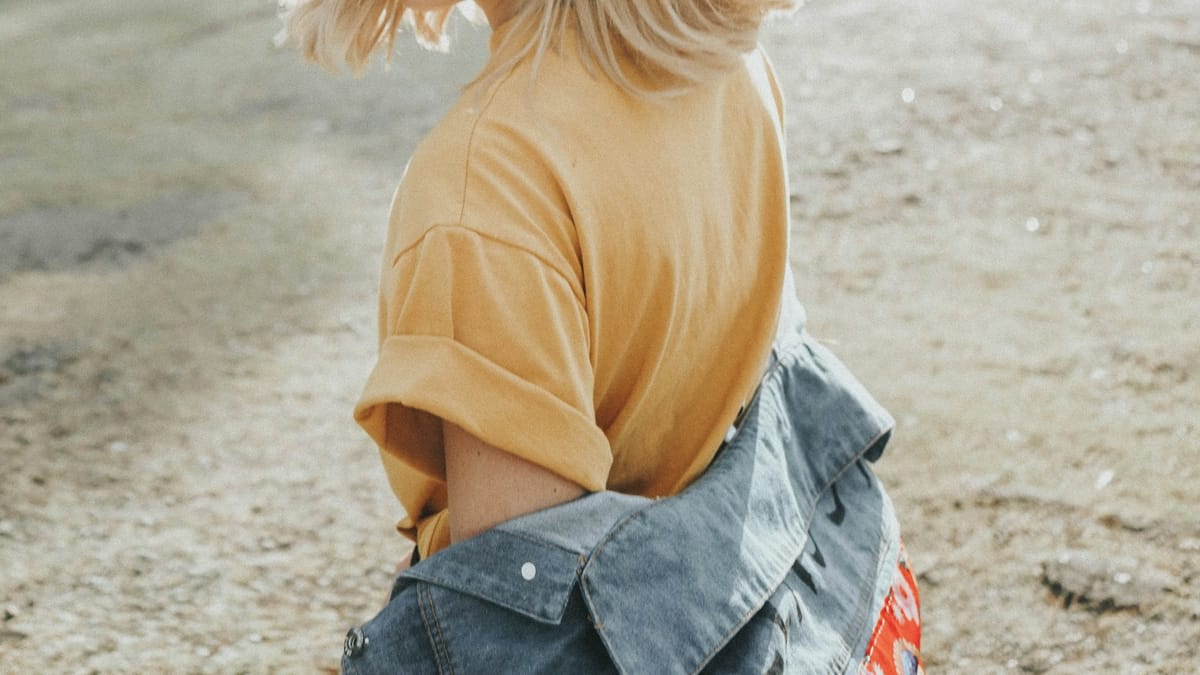 Mujer sonriendo bajo la luz del sol entre árboles