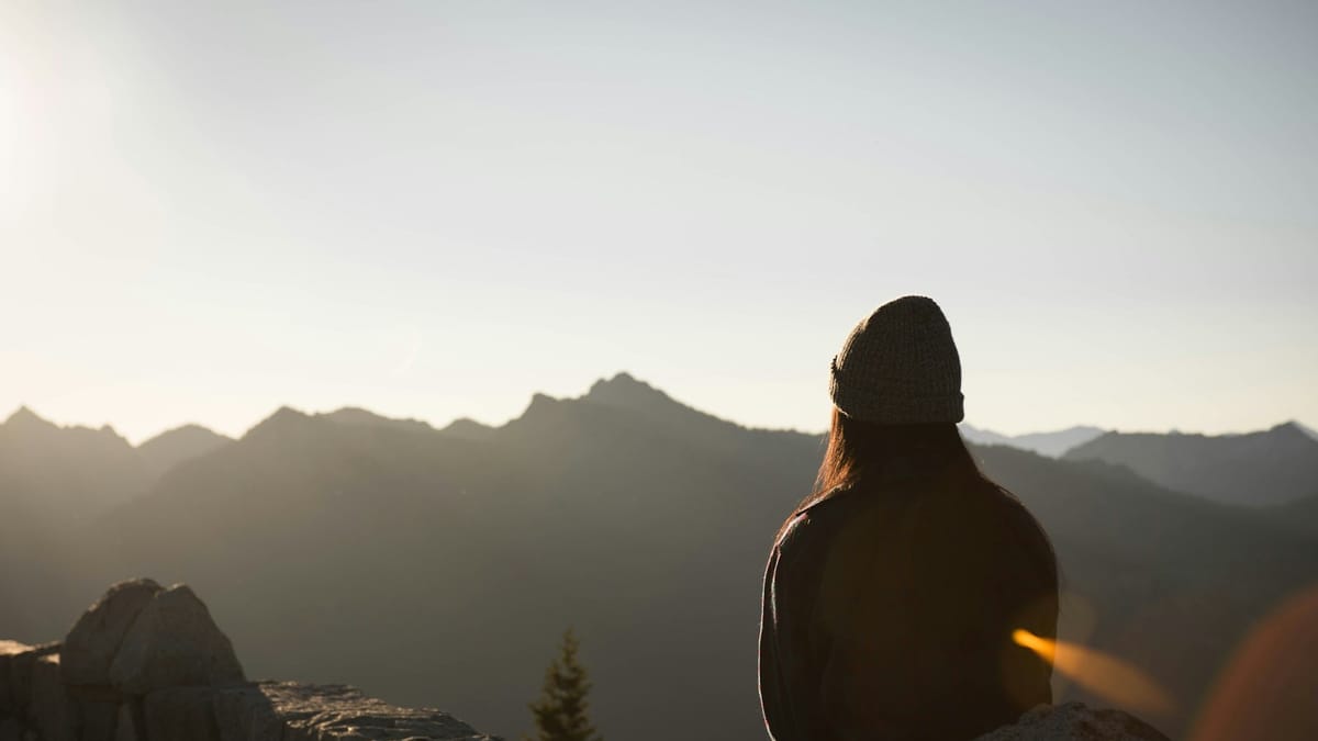 Mujer sentada en la montaña contemplando el amanecer