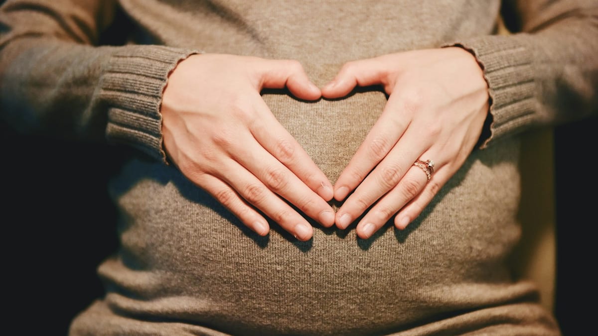 Manos formando un corazón sobre un vientre embarazado