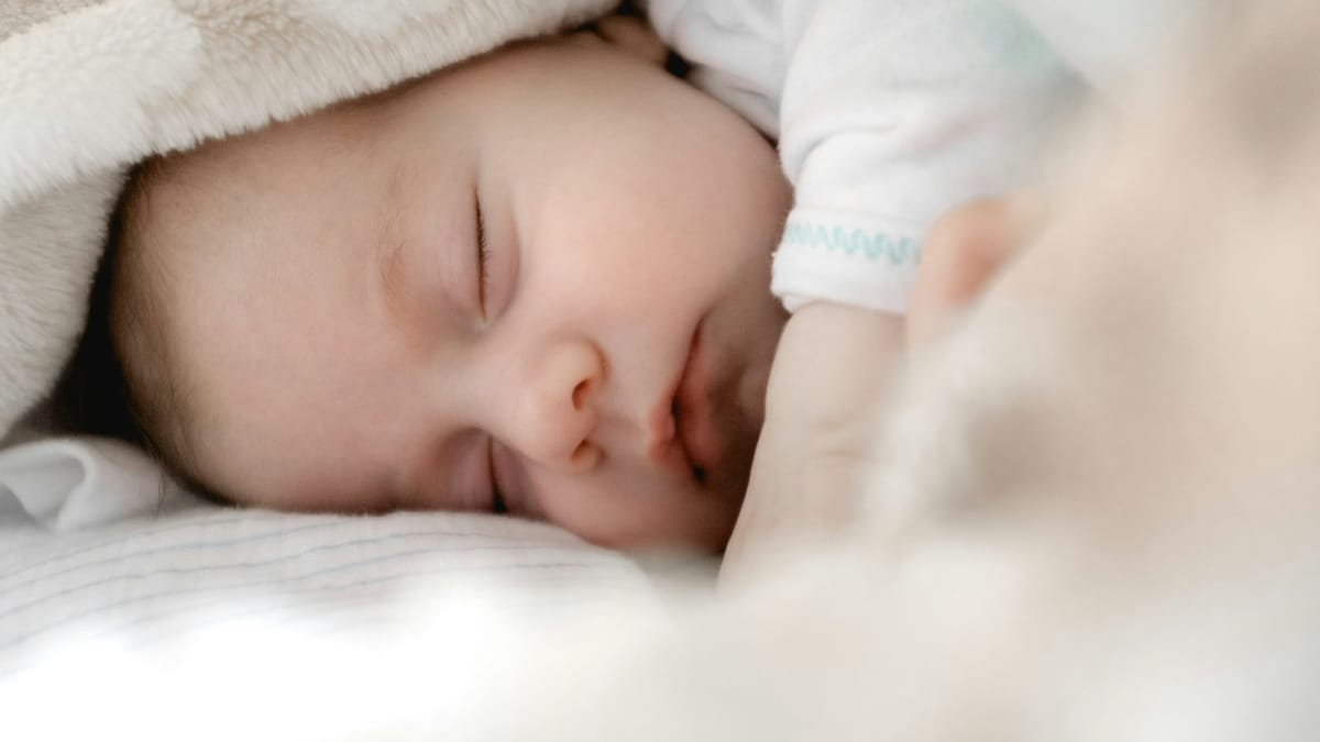 Bebé durmiendo plácidamente la siesta sobre una manta blanca